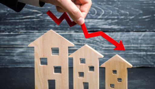 a decline in property prices shown as a red arrow going down above three wooden houses