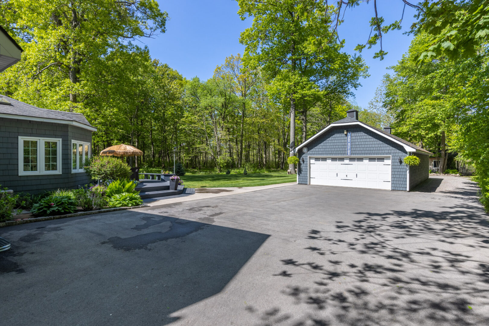 A large paved parking area in front of a large cottage and a big detached garage.