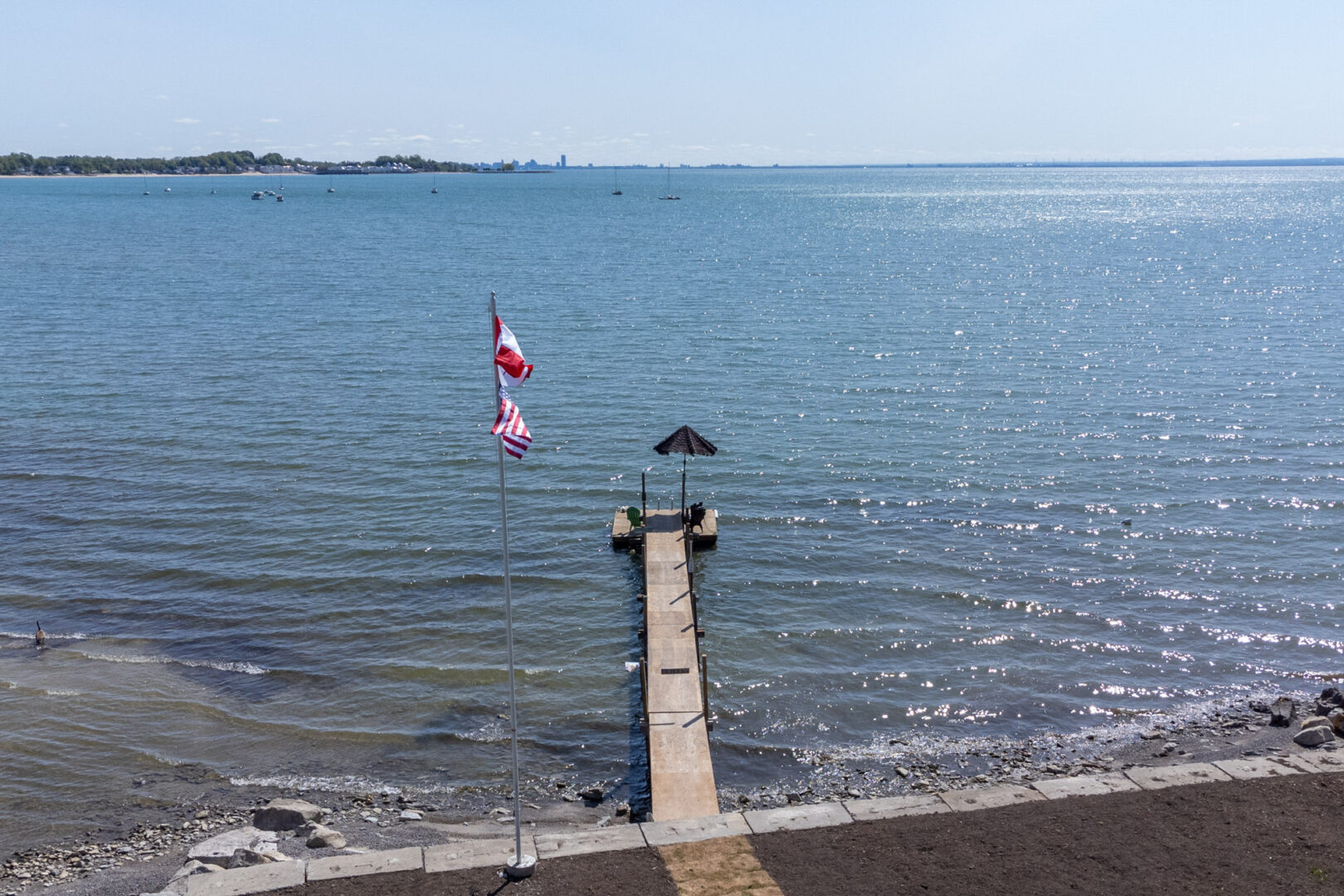 A private, narrow dock stretches into a blue lake.