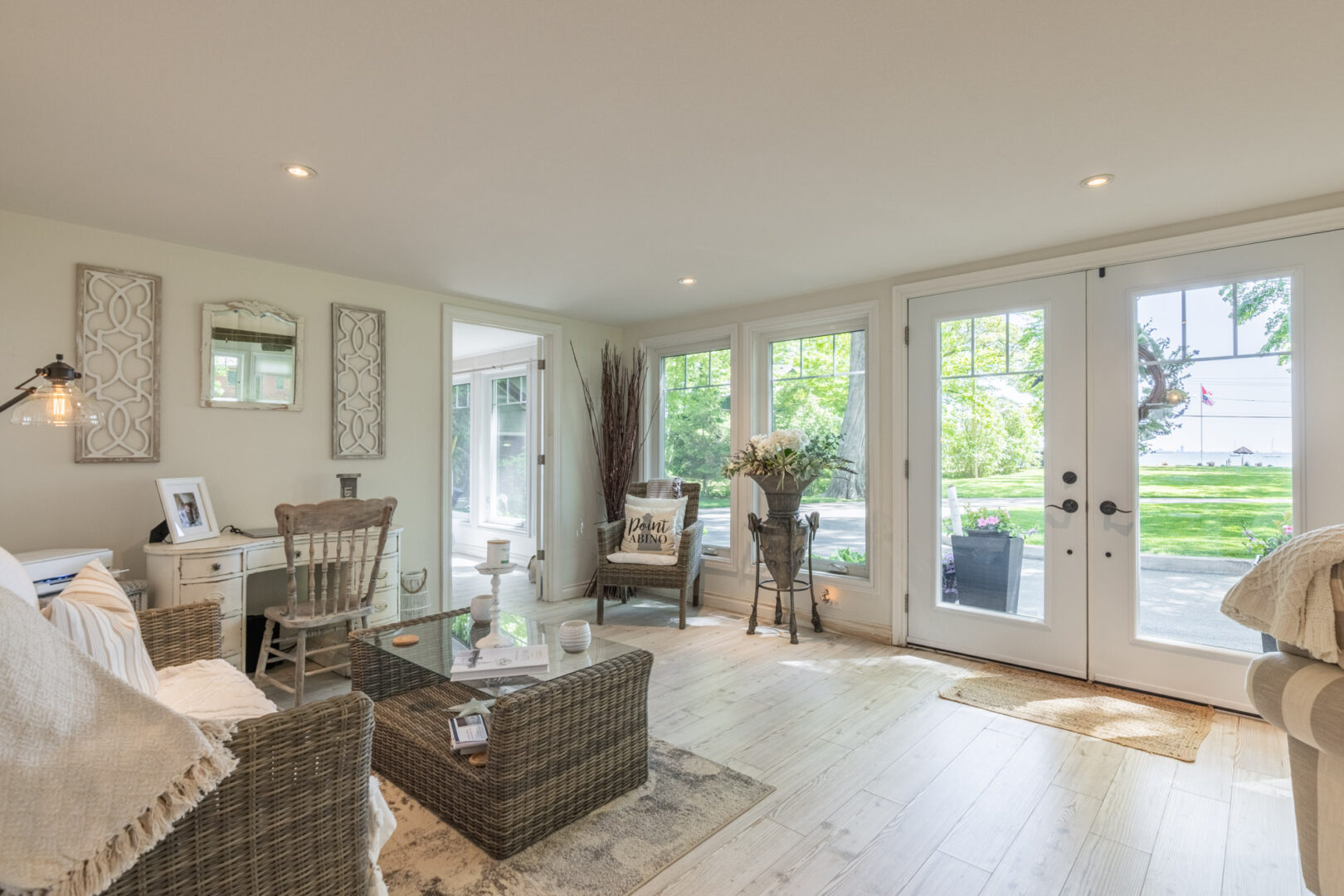 A bright indoor space with a couch and a coffee table, a desk, and double doors leading outdoors.