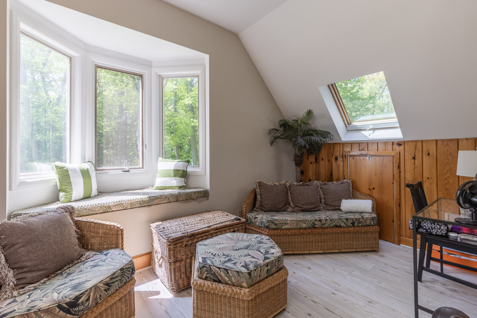 A small second-floor loft sitting area with sloping ceilings, lots of windows, and seating.