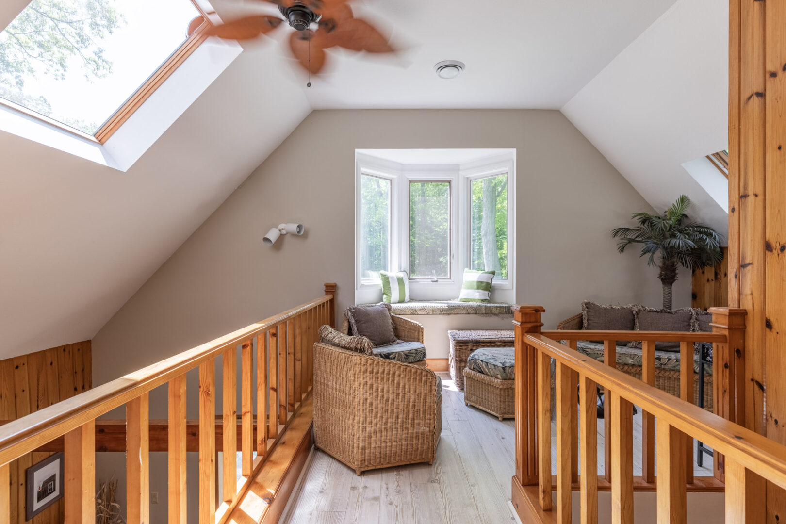 An upper-level walkway with a railing, leading to a small loft sitting area.