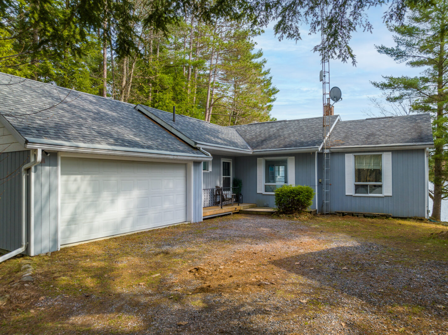 A single-storey cottage surrounded by trees, with a big garage.