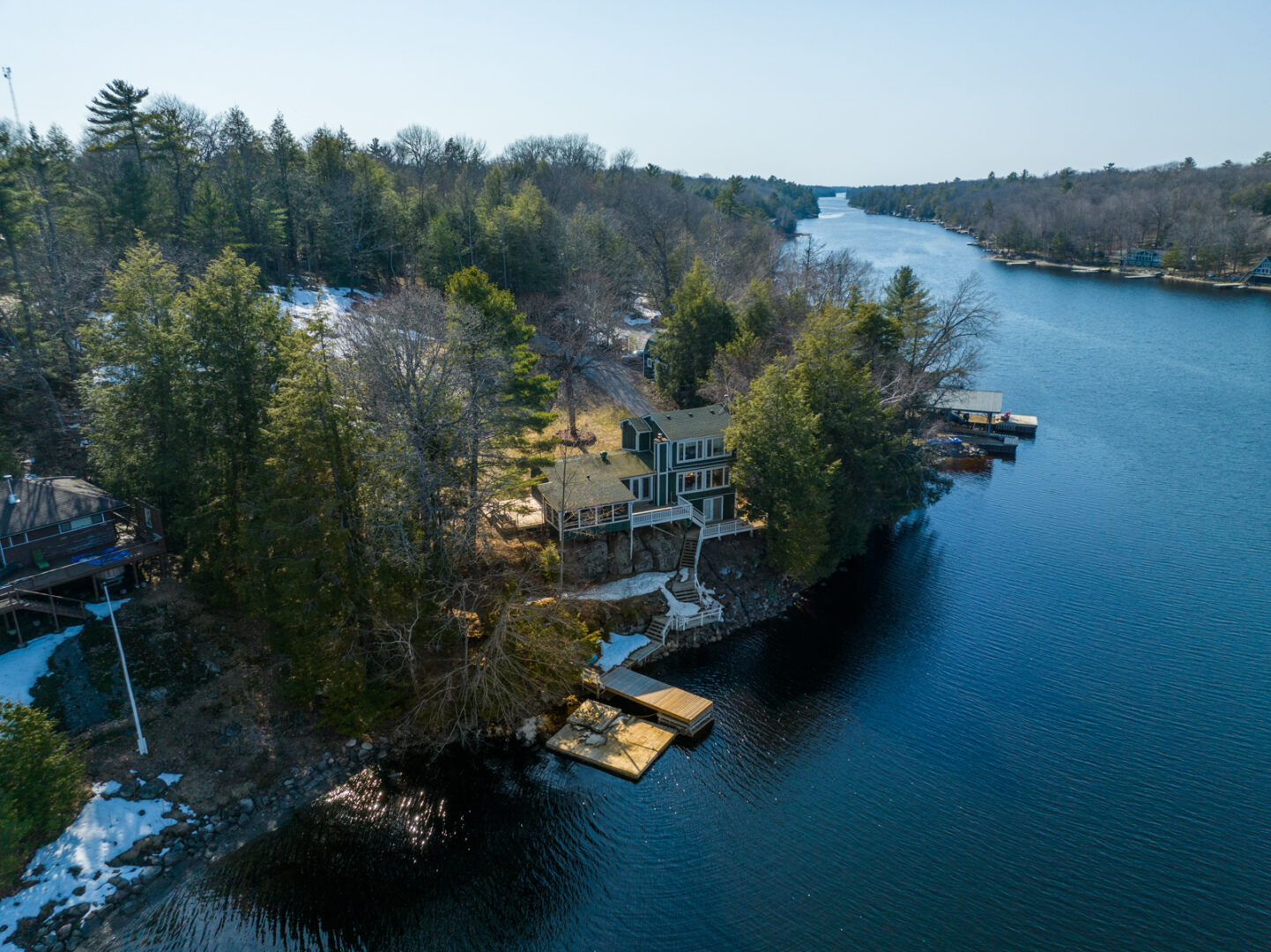 A big cottage sits on the shoreline of a wide stretch of lake.