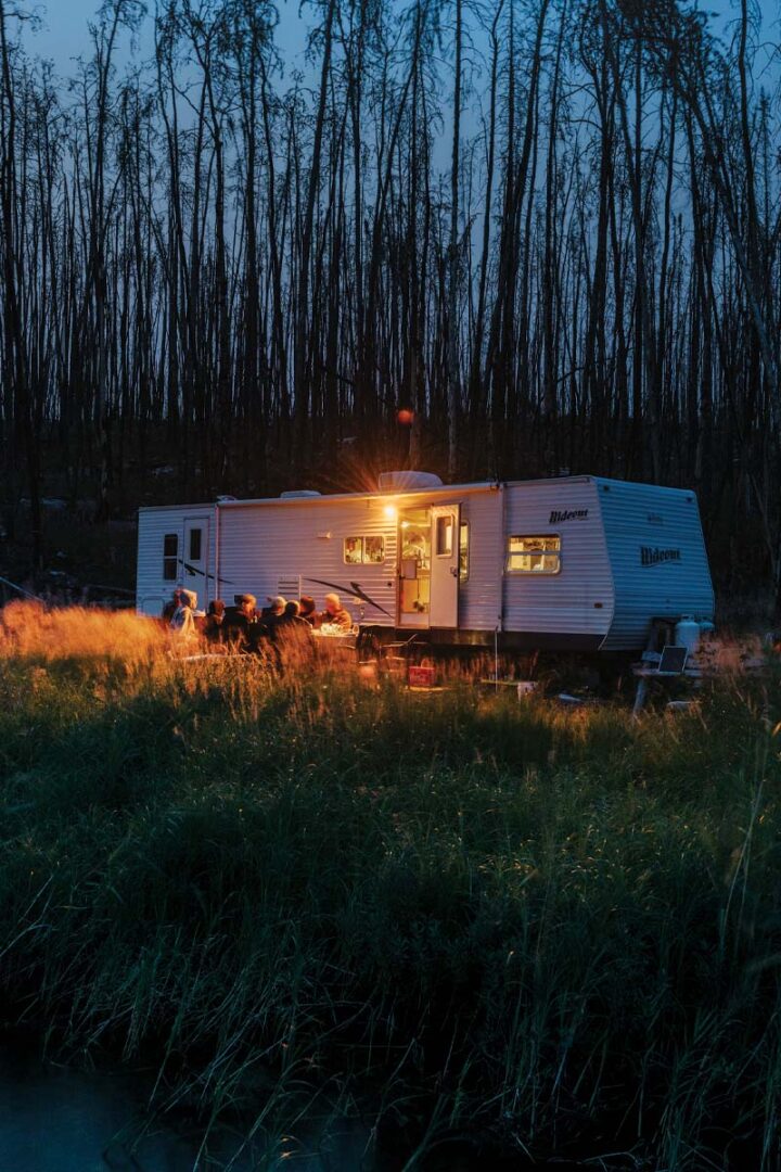 Woodsworths host a dinner party outside their RV at dusk