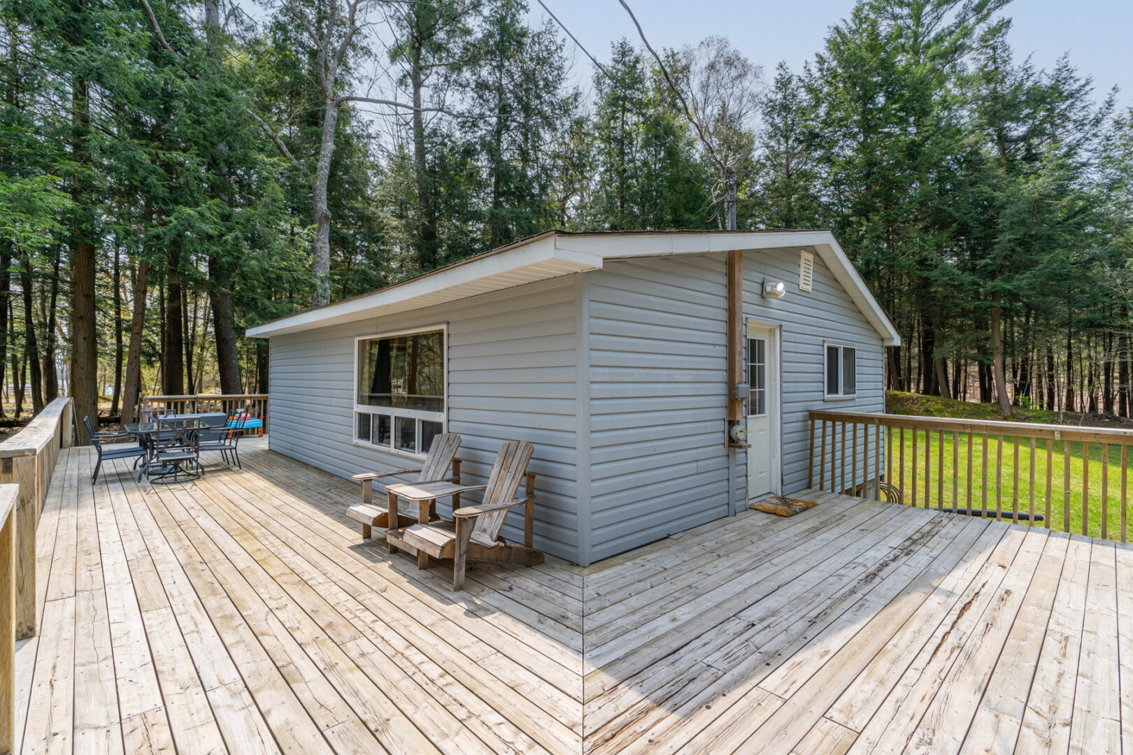 A large deck wraps around the corner of a small cottage.