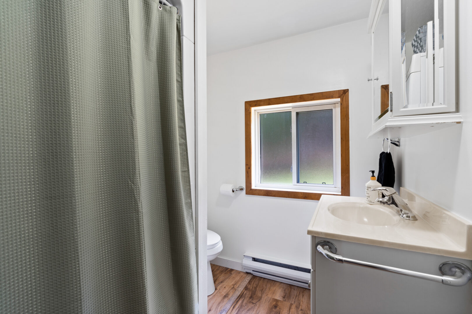 A small bathroom with a shower, a toilet, a sink, and a window.