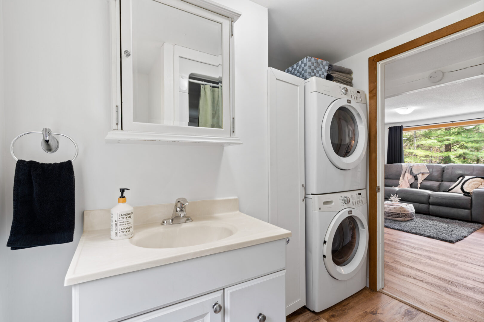 A stacked washing machine and dryer sit next to the sink in a small washroom area.