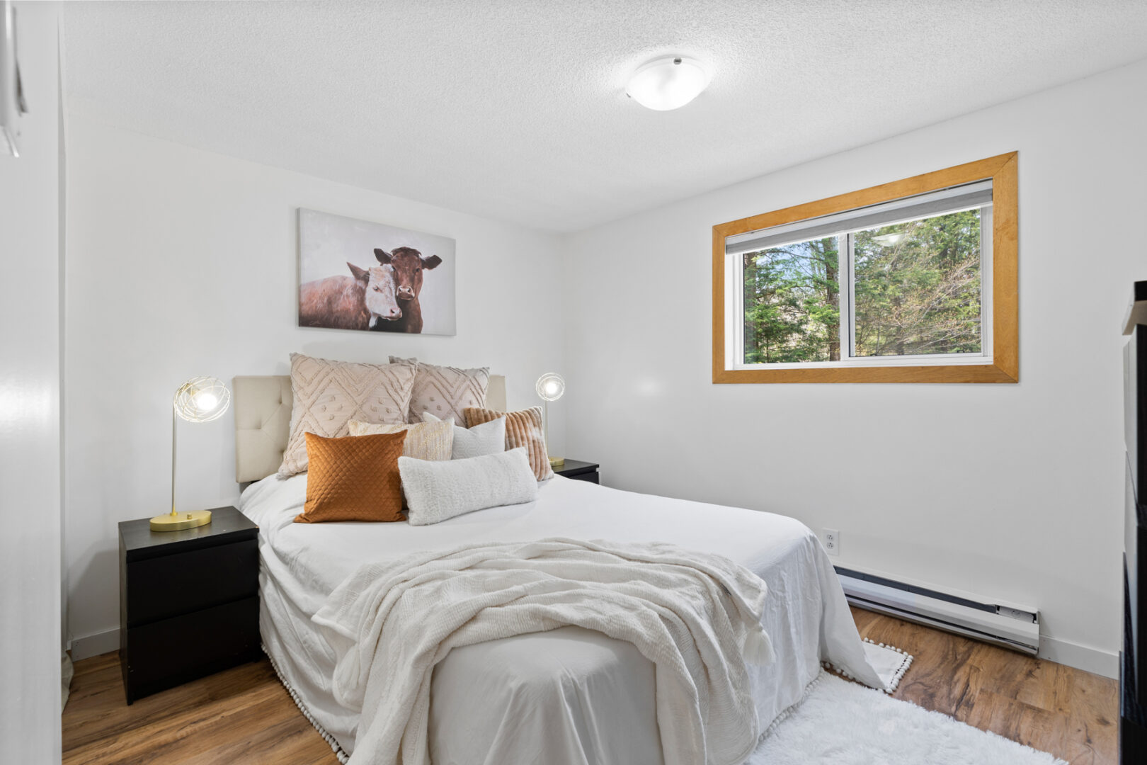 A bright bedroom with a large bed, white walls, and a window.