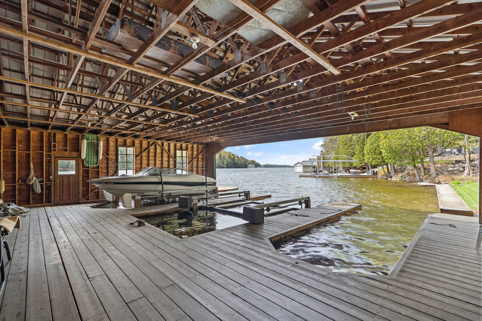 Interior of a large boathouse, looking out into the lake.