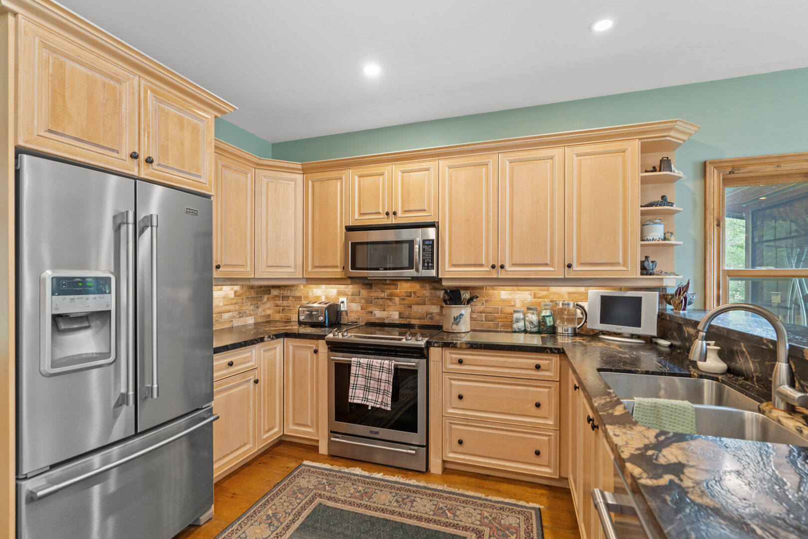 A bright kitchen with modern appliances, light wood cupboards, and lots of counter space.