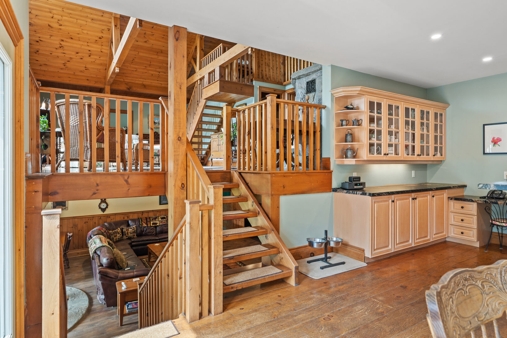 An open-concept living space has stairs that lead both up and down into two large living areas.