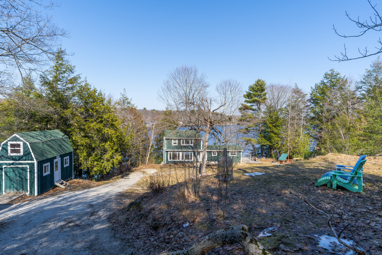 A long driveway leads to a big cottage and a small bunkie surrounded by trees.
