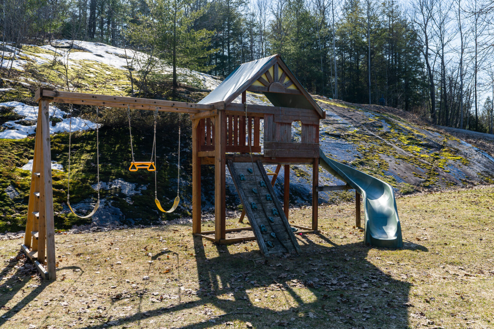 An outdoor play set with swings and a slide.