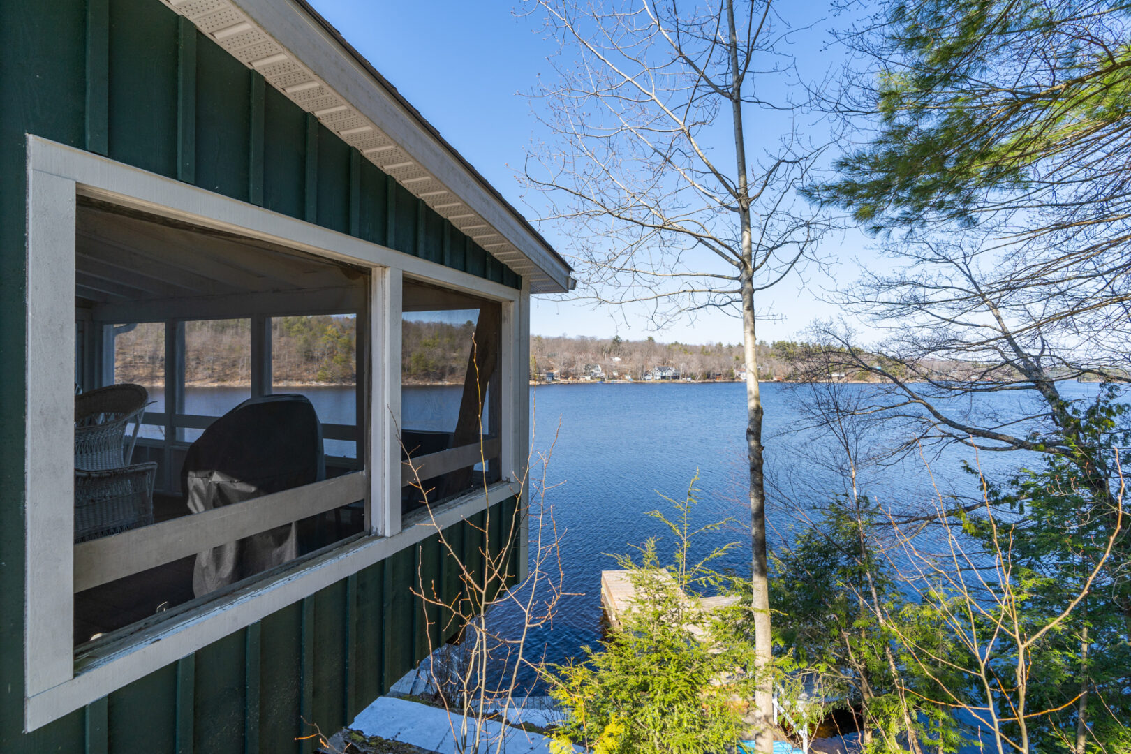 The exterior edge of a screened-in porch overlooking a lake.