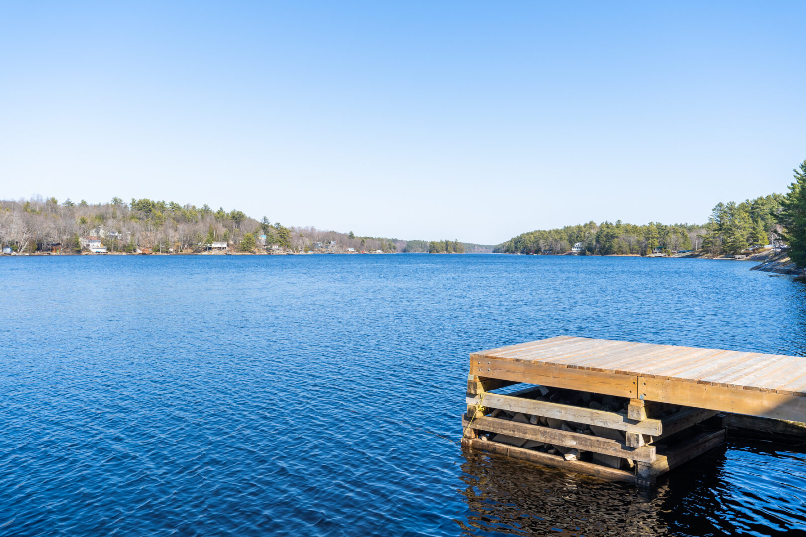 A wooden dock extends into a still, blue lake.