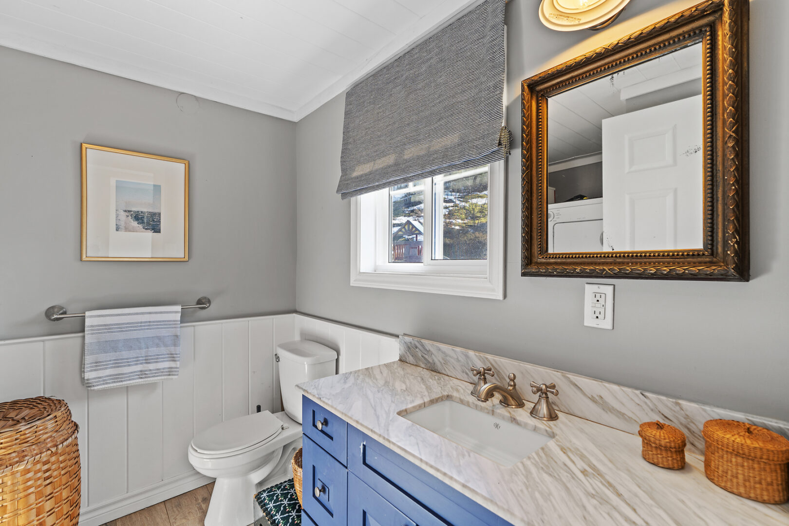 A bright bathroom with a toilet, a sink, and blue cabinets.