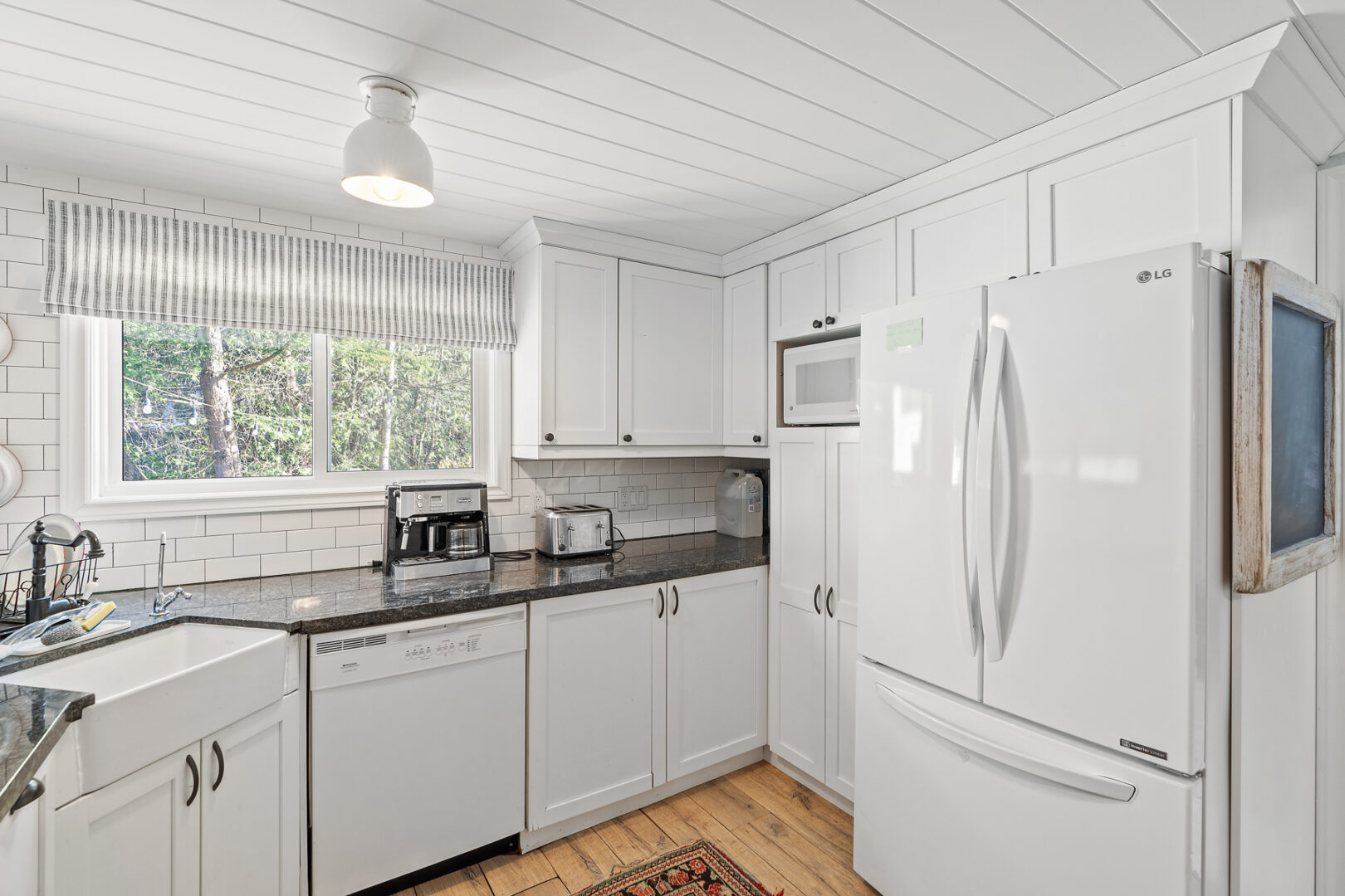 A bright cottage kitchen with white cupboards and appliances.