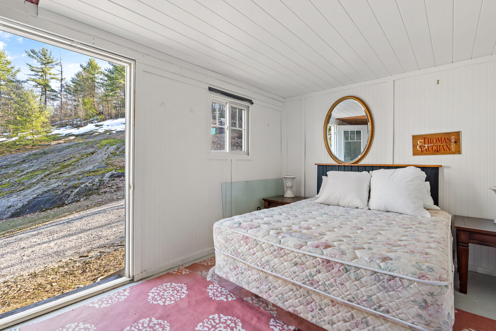 A bright, airy bunkie space with a bed, a large doorway, and a patterned floor.