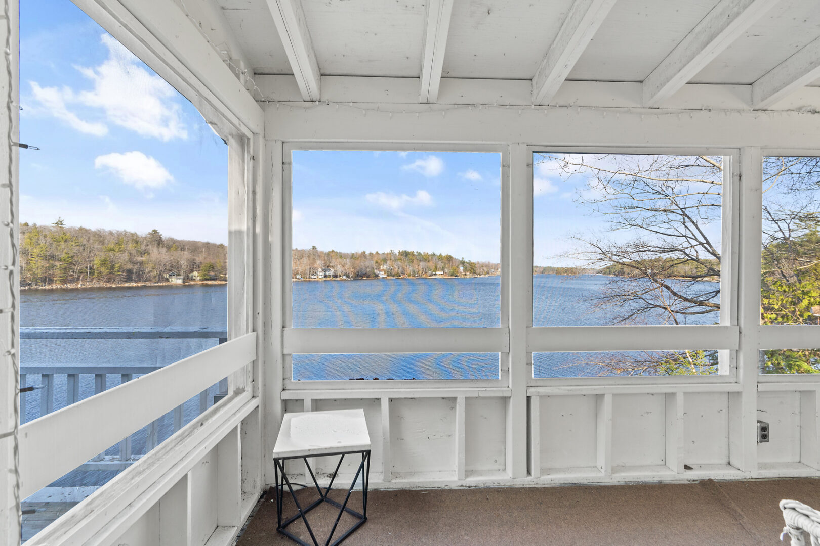 A screened-in porch area overlooking a lake.