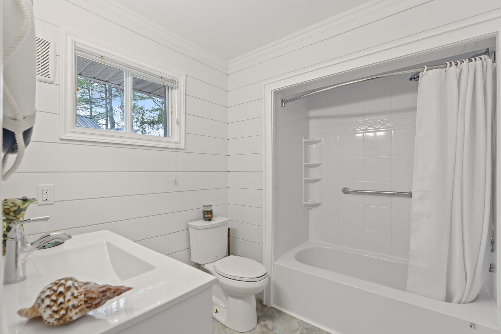 A bathroom with white walls, a toilet, a sink, and a shower/tub combo.
