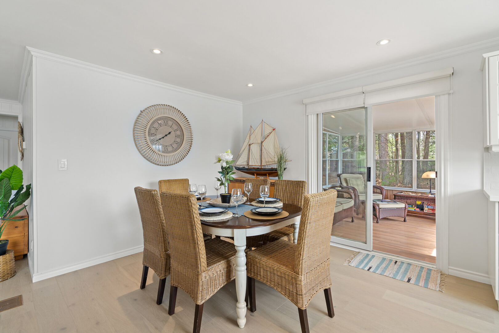 A small, bright dining area with a table and chairs. A sunroom branches off through doors off to the side.