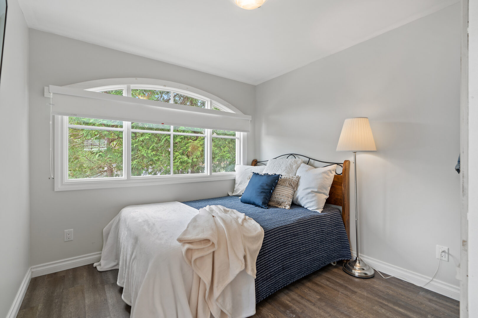 A small bed in front of a large window, in a bunkie living space.