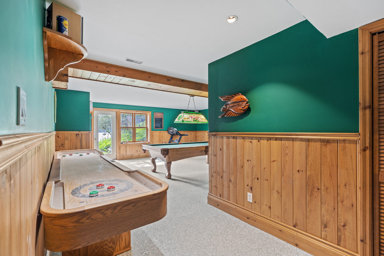 A big games room with a billiard table and a shuffleboard table.