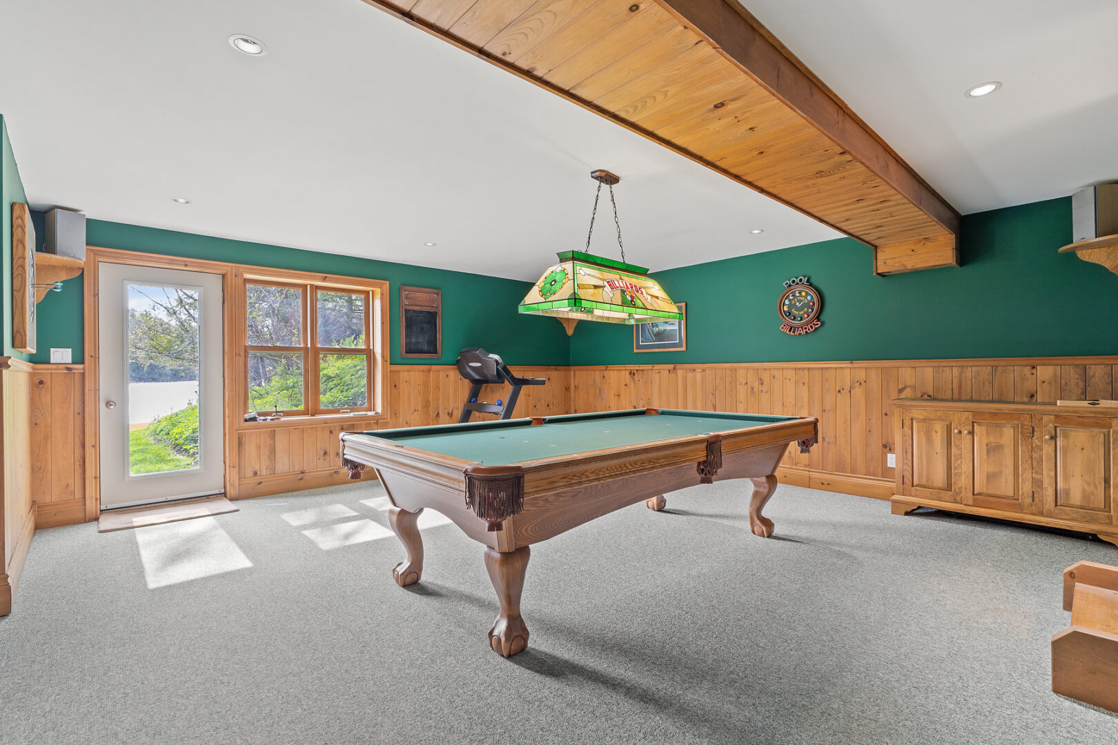 A big games room with a billiard table and a door leading out to a back lawn area.