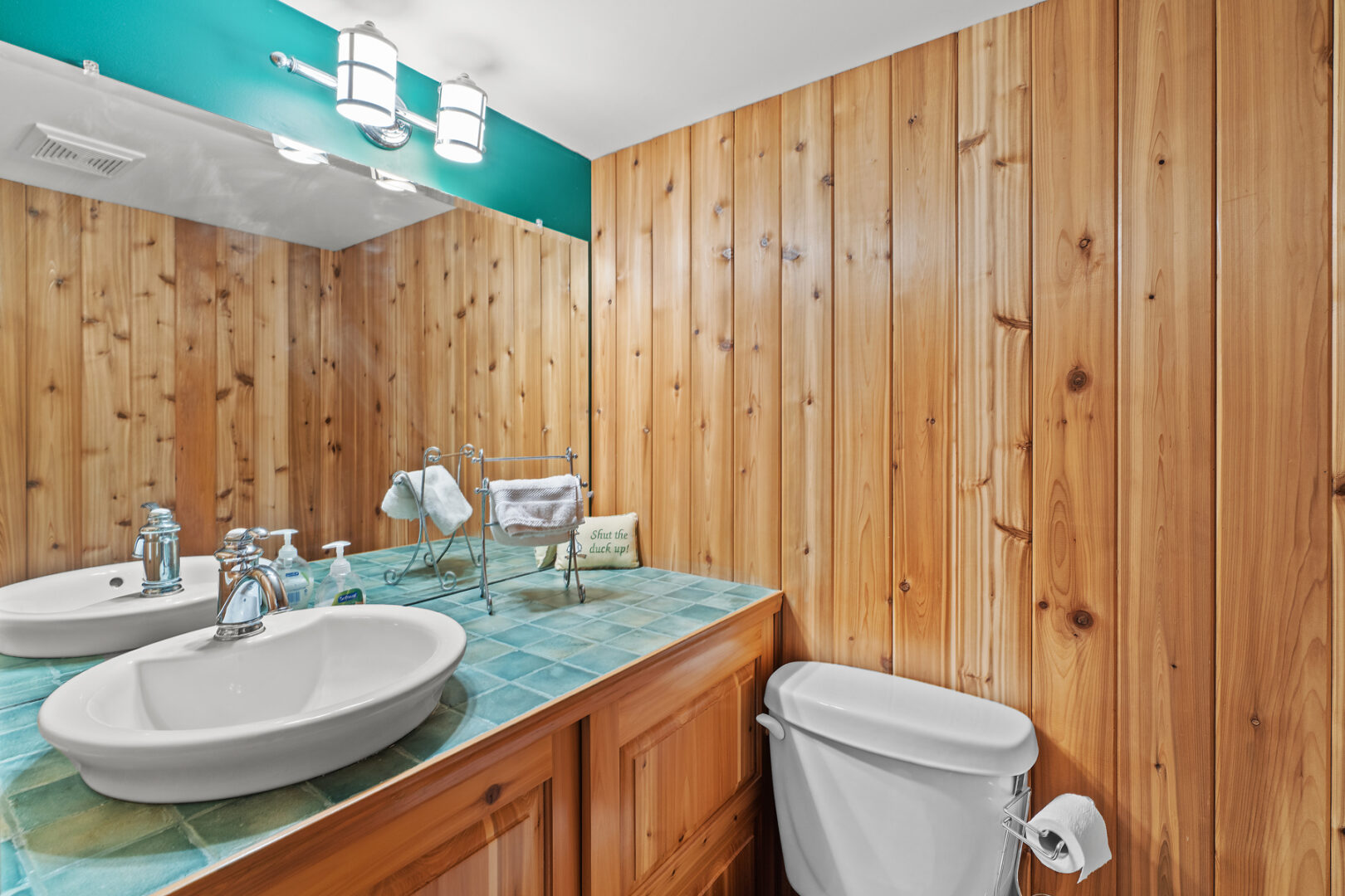 A small bathroom with wood-panelled walls, a toilet, and a sink.