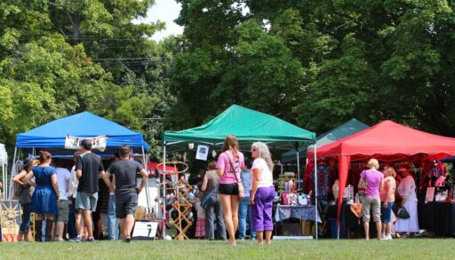 People stand in front of tents at outdoor market
