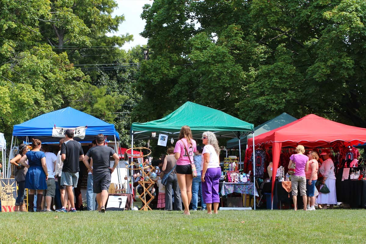 People stand in front of tents at outdoor market