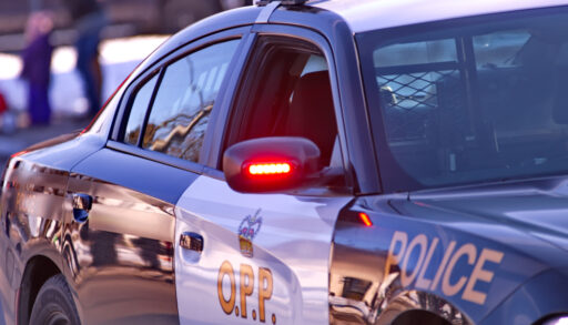 Showing an Ontario Provincial Police cruiser with a side mirror flashing red light and O.P.P. and POLICE decals affixed.