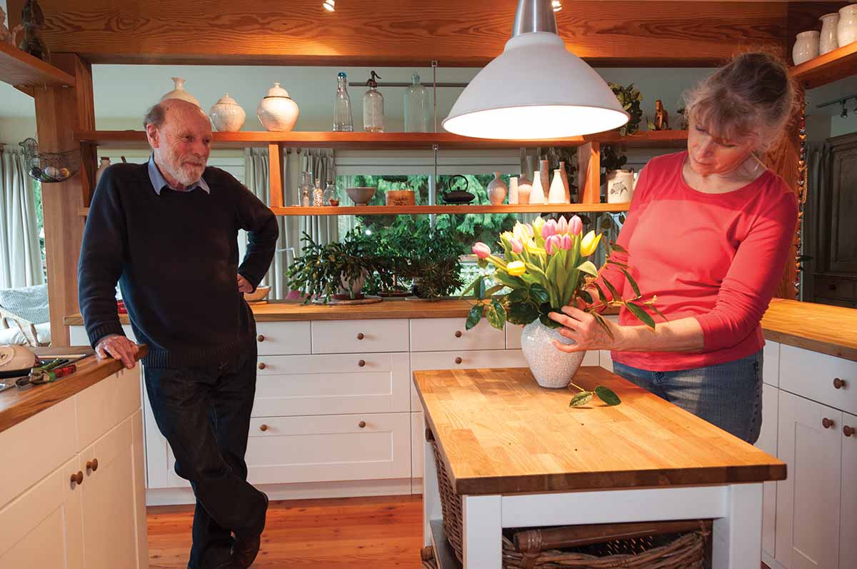 Paul and Babette Deggan in their kitchen. Babette arranges flowers in one of her pottery pieces