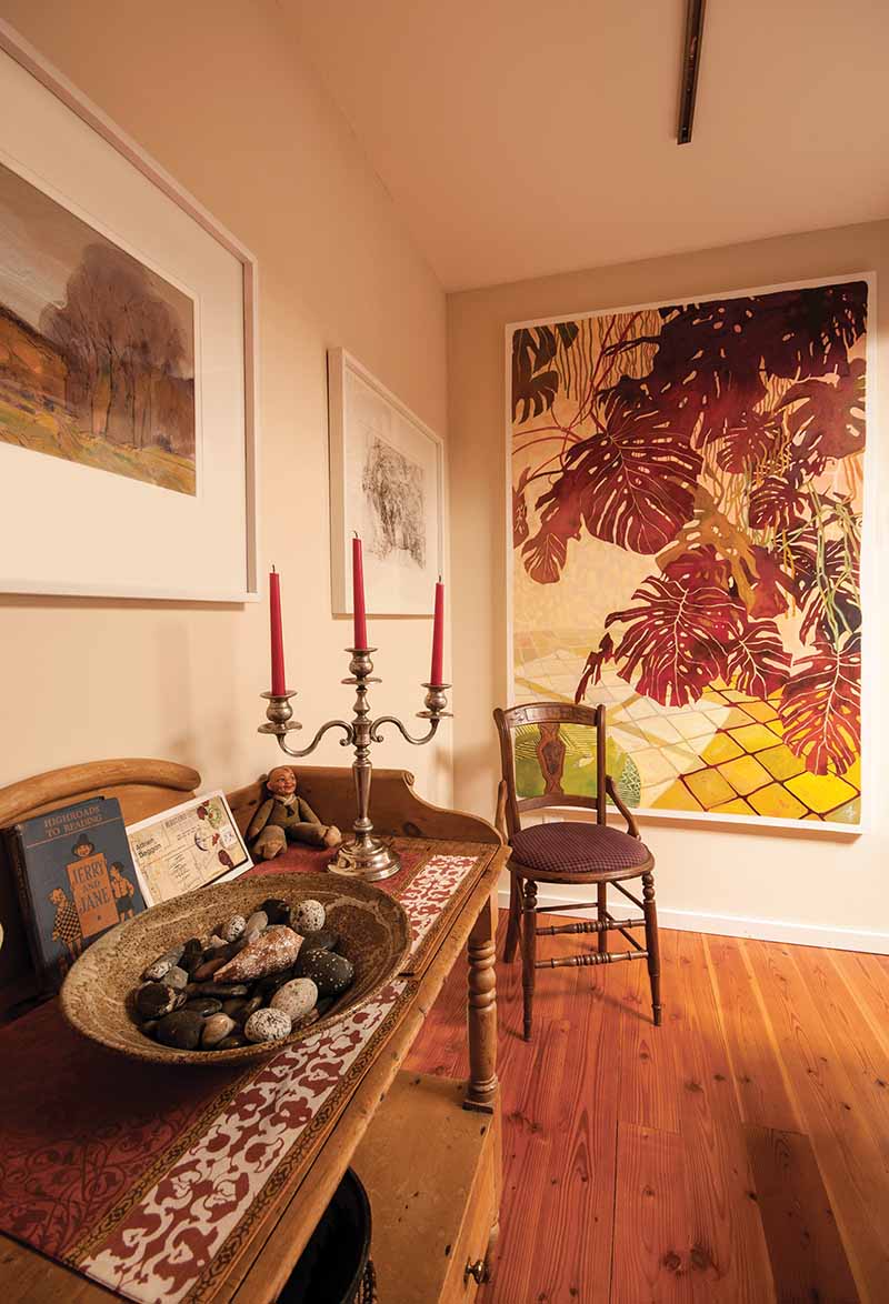 The family’s collection of B.C. beach stones fills one of Babette’s pottery bowls on an antique washstand in their living room. Just beyond is son Adrien’s painting titled Green Cat and Philodendron.