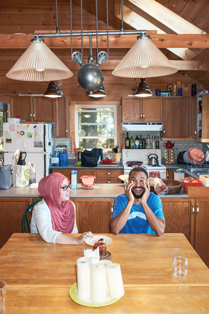Lucie and Ahmed sit at kitchen table laughing