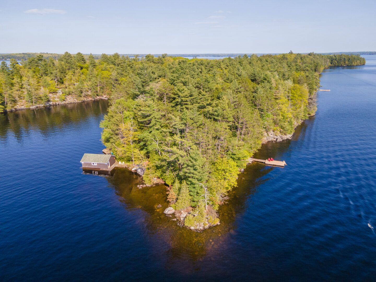 Overhead view of the point of an angular peninsula on a lake island, surrounded by deep blue lake.