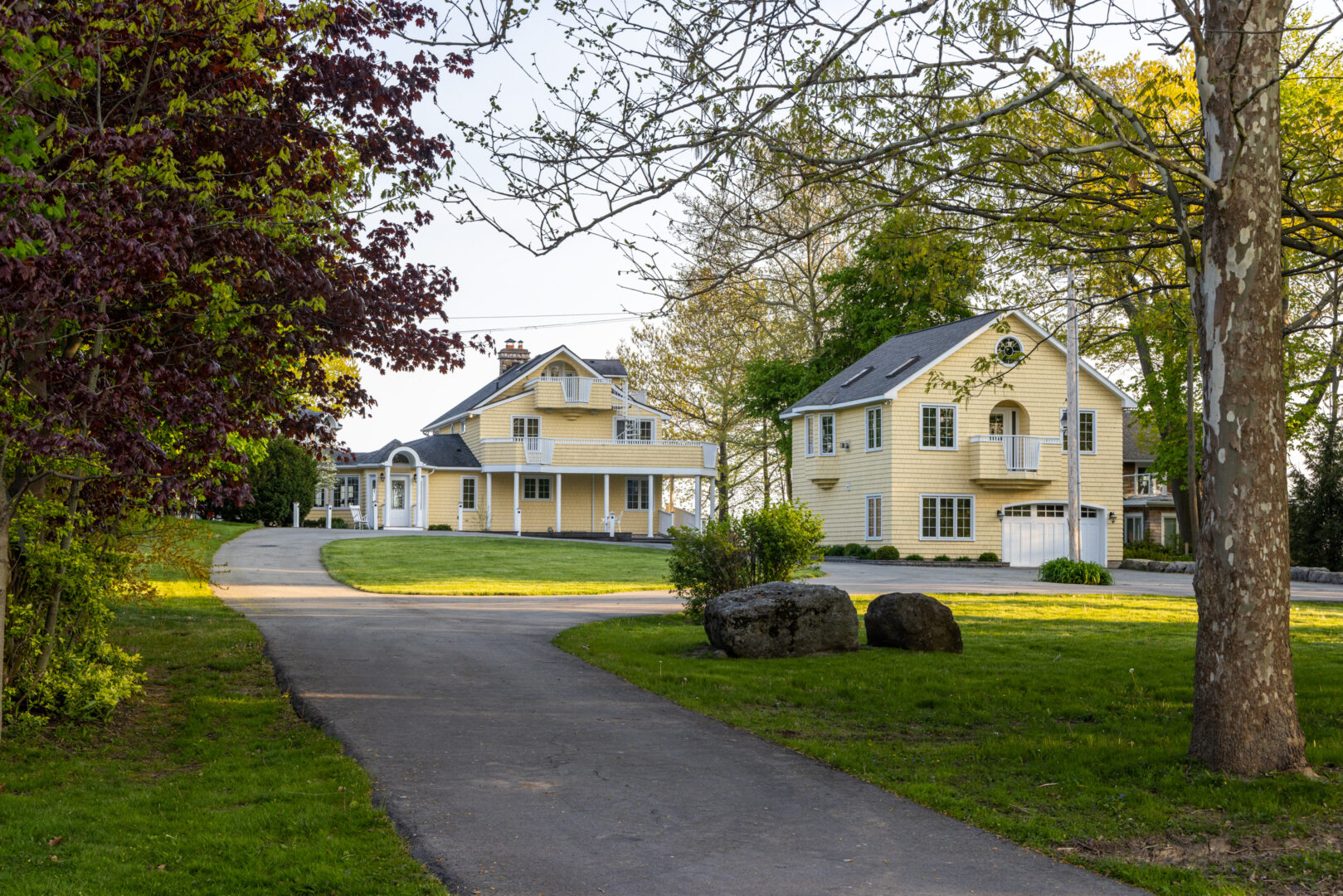 A long paved driveway leads to two large, pale yellow buildings: a main cottage and a guest house.