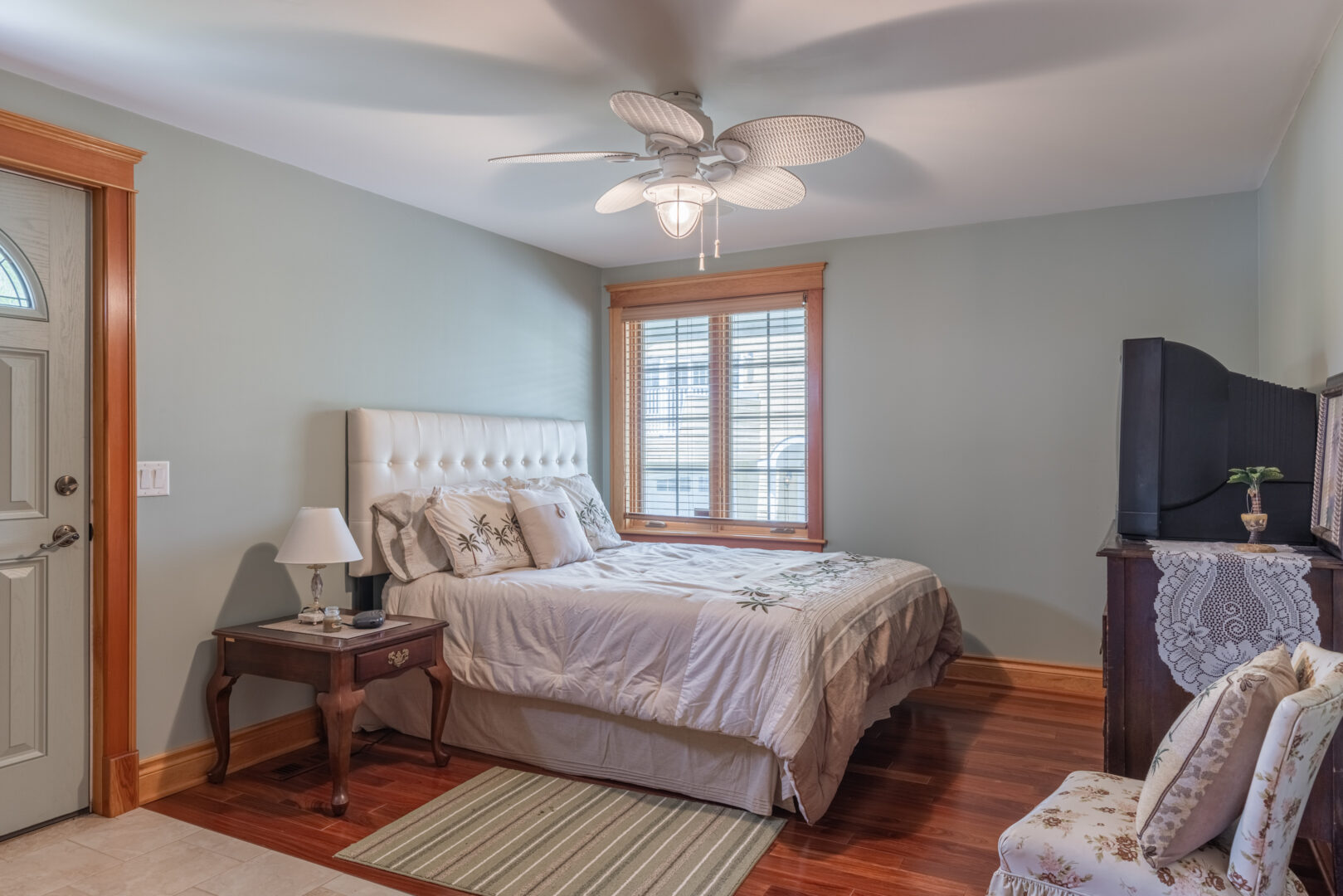 A bright bedroom with a small bed, a window, a pale blue walls.