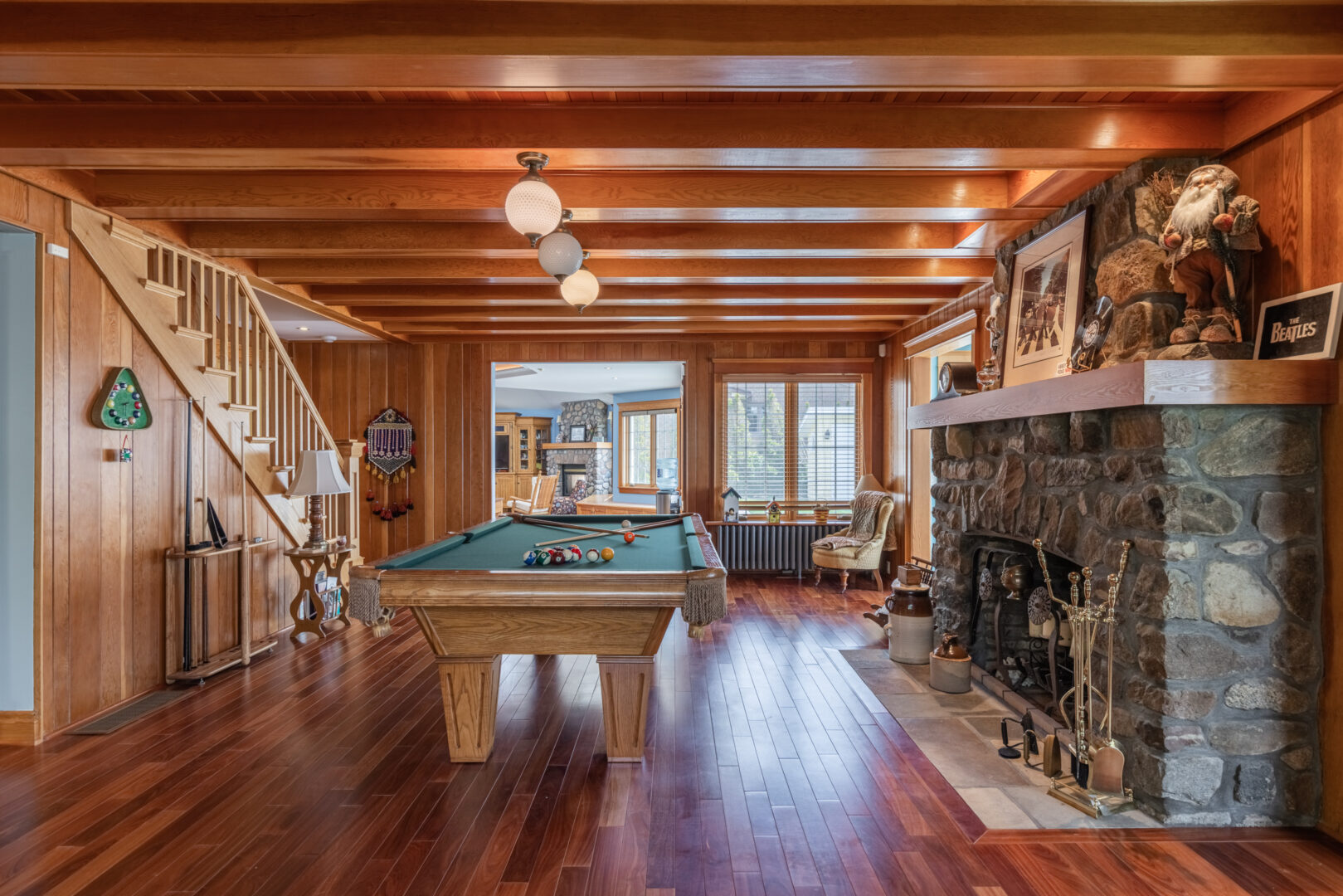 A large room with a pool table and a stone fireplace.
