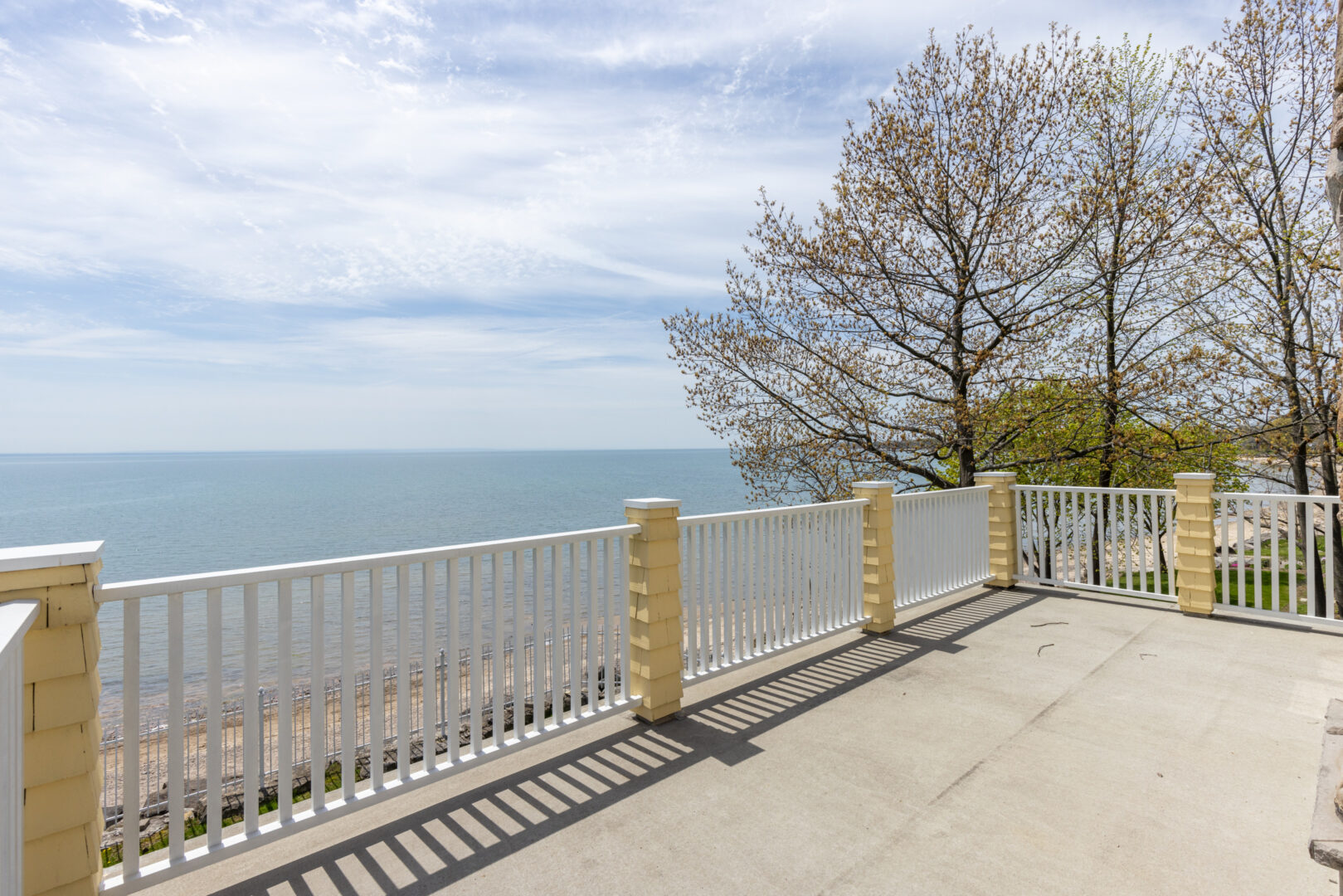 A large balcony with a while railing, overlooking a lake.