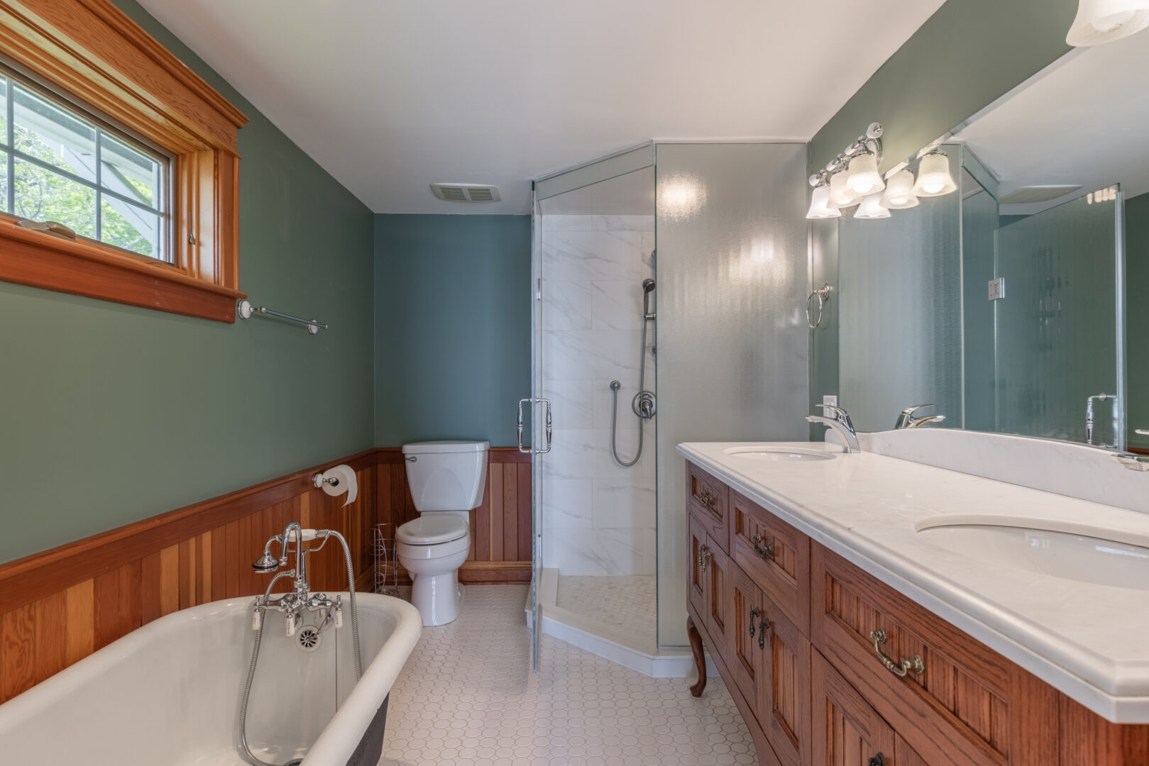 A large ensuite bathroom with blue walls, a toilet, a sink, and a walk-in shower.