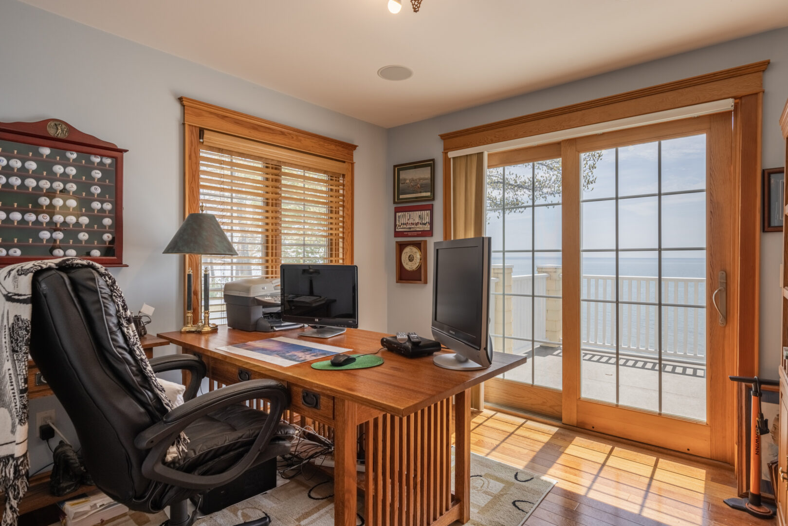 A bright home office area with a desk, a chair, and double doors leading out to a balcony.