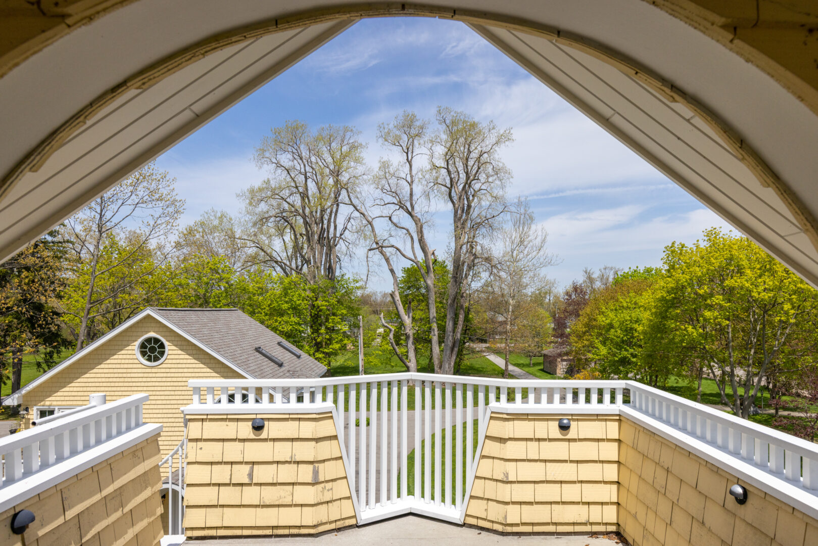 A small balcony with a white railing, off an attic bedroom.