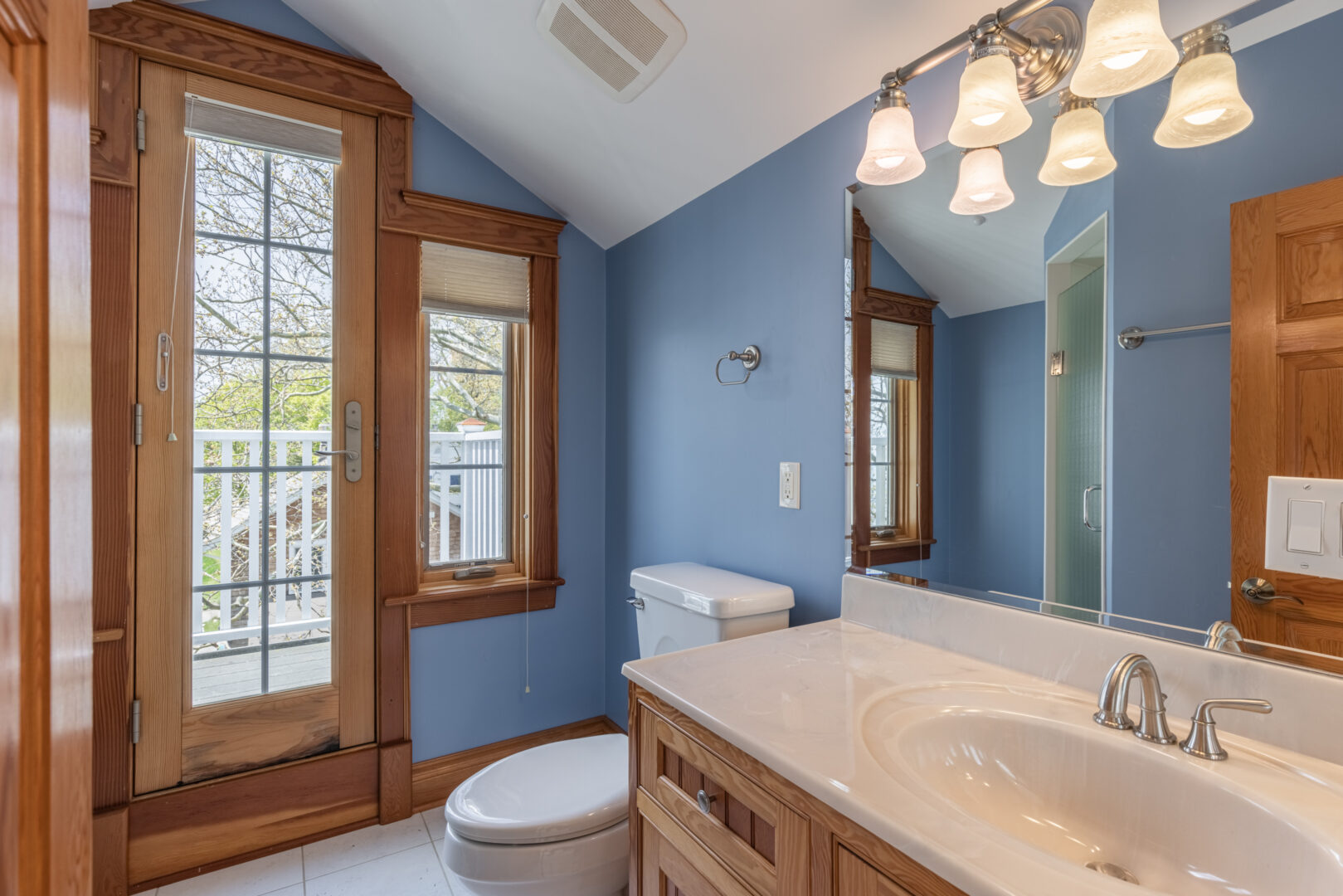 A bright bathroom with blue walls, a toilet, and a sink.