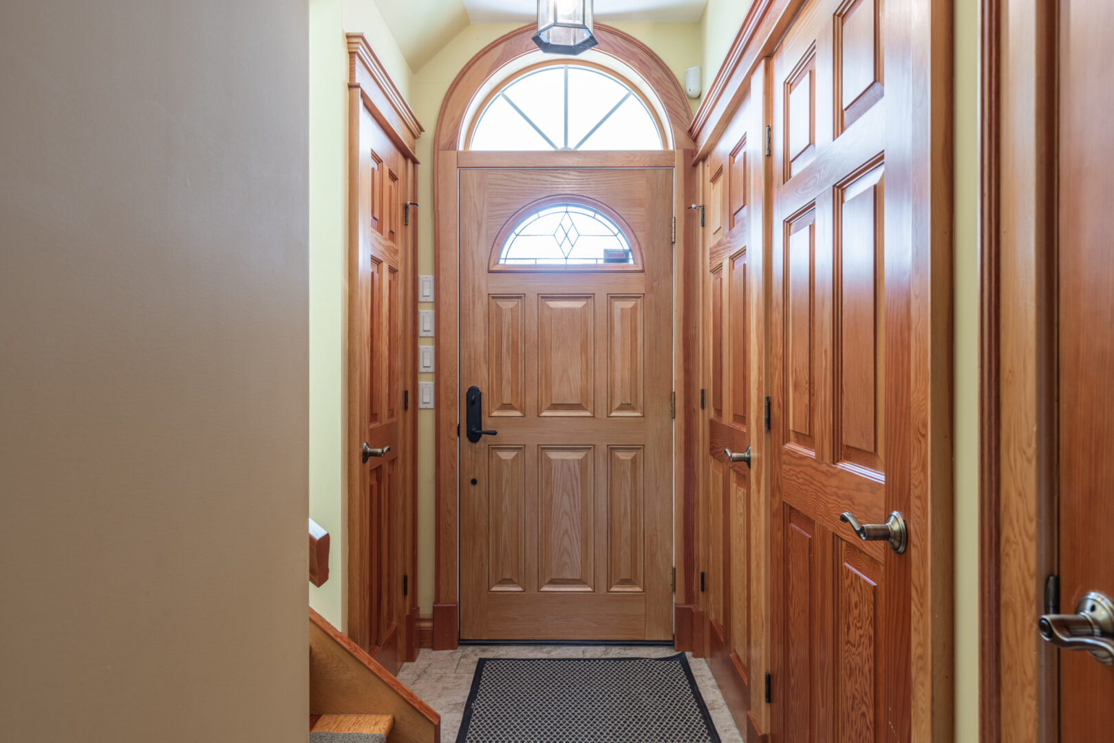 Narrow entrance of a lake property guest house with large wooden closet doors just past the front door.