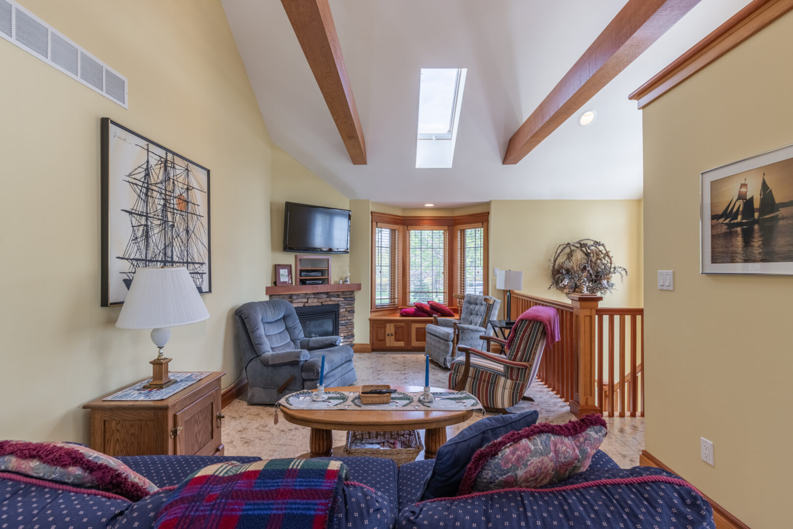 A small living area with a couch, a few chairs, high ceilings and a big window.