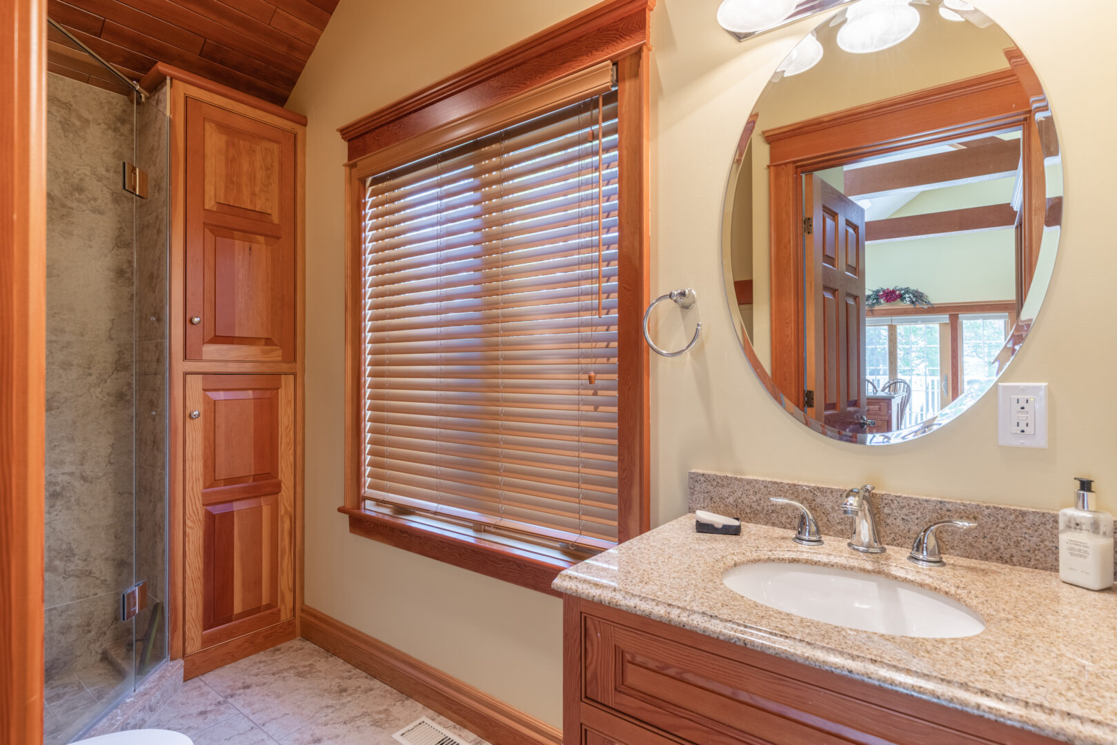 A small bathroom with a walk-in shower, a sink, and a large window.
