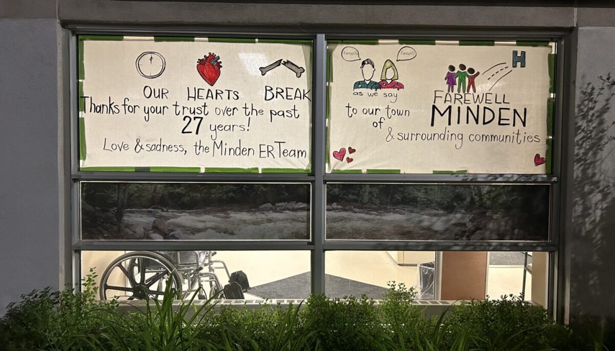 Handwritten signs on Minden ER windows. Text: "Our hearts break as we say farewell to our town of Minden & surrounding communities. Thanks for your trust over the past 27 years! Love & sadness, the Minden ER team."
