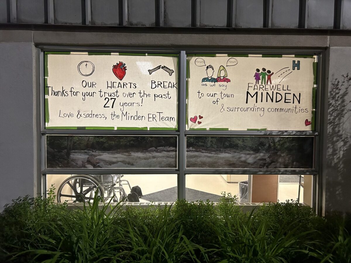 Handwritten signs on Minden ER windows. Text: "Our hearts break as we say farewell to our town of Minden & surrounding communities. Thanks for your trust over the past 27 years! Love & sadness, the Minden ER team."